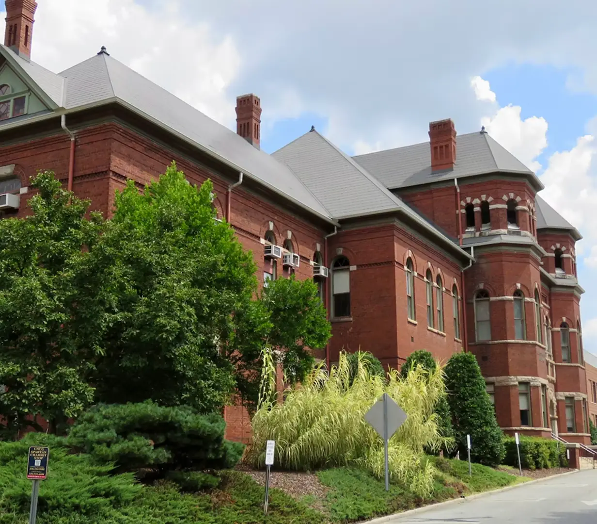 Historic Victorian brick building with turrets in downtown Greensboro, North Carolina, on the streets charter bus operators navigate near the Tanger Center