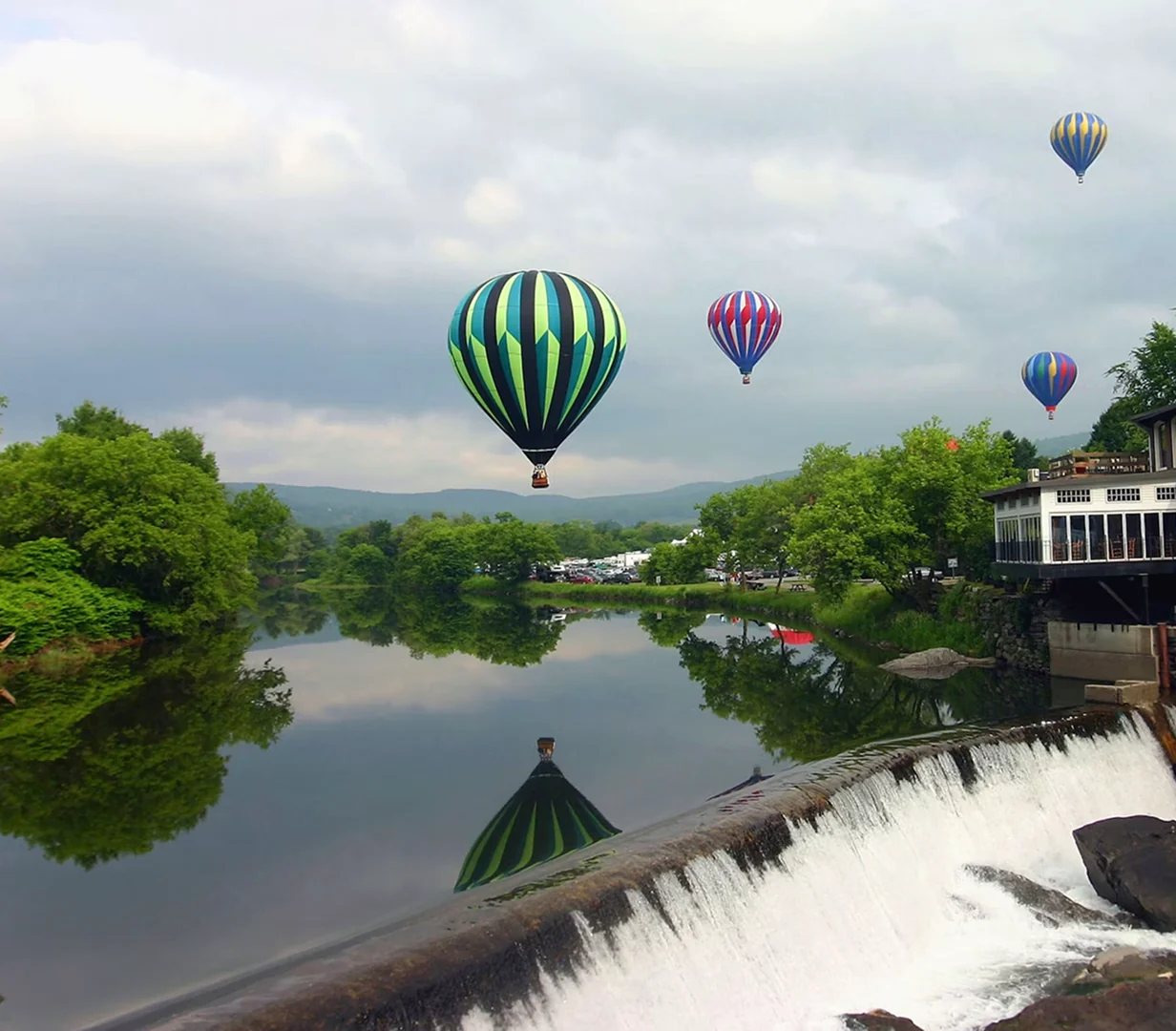 Hot air balloons over a river waterfall outside Hartford, Connecticut, day-trip scenery for charter bus groups