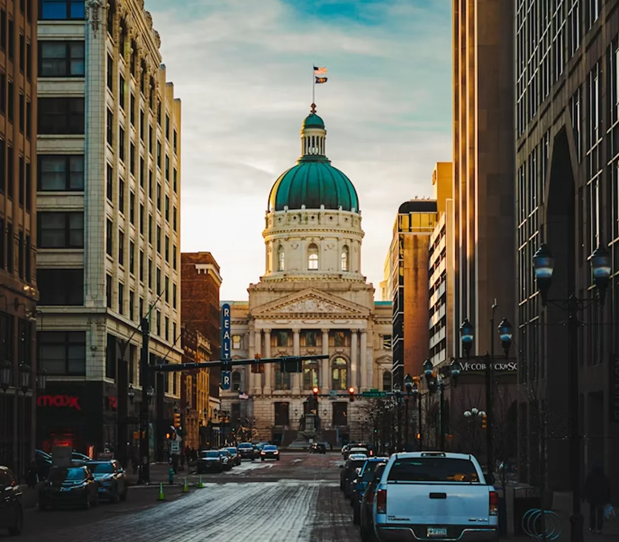 Green dome of the Indiana Statehouse above a downtown Indianapolis street, on the routes charter bus operators run daily