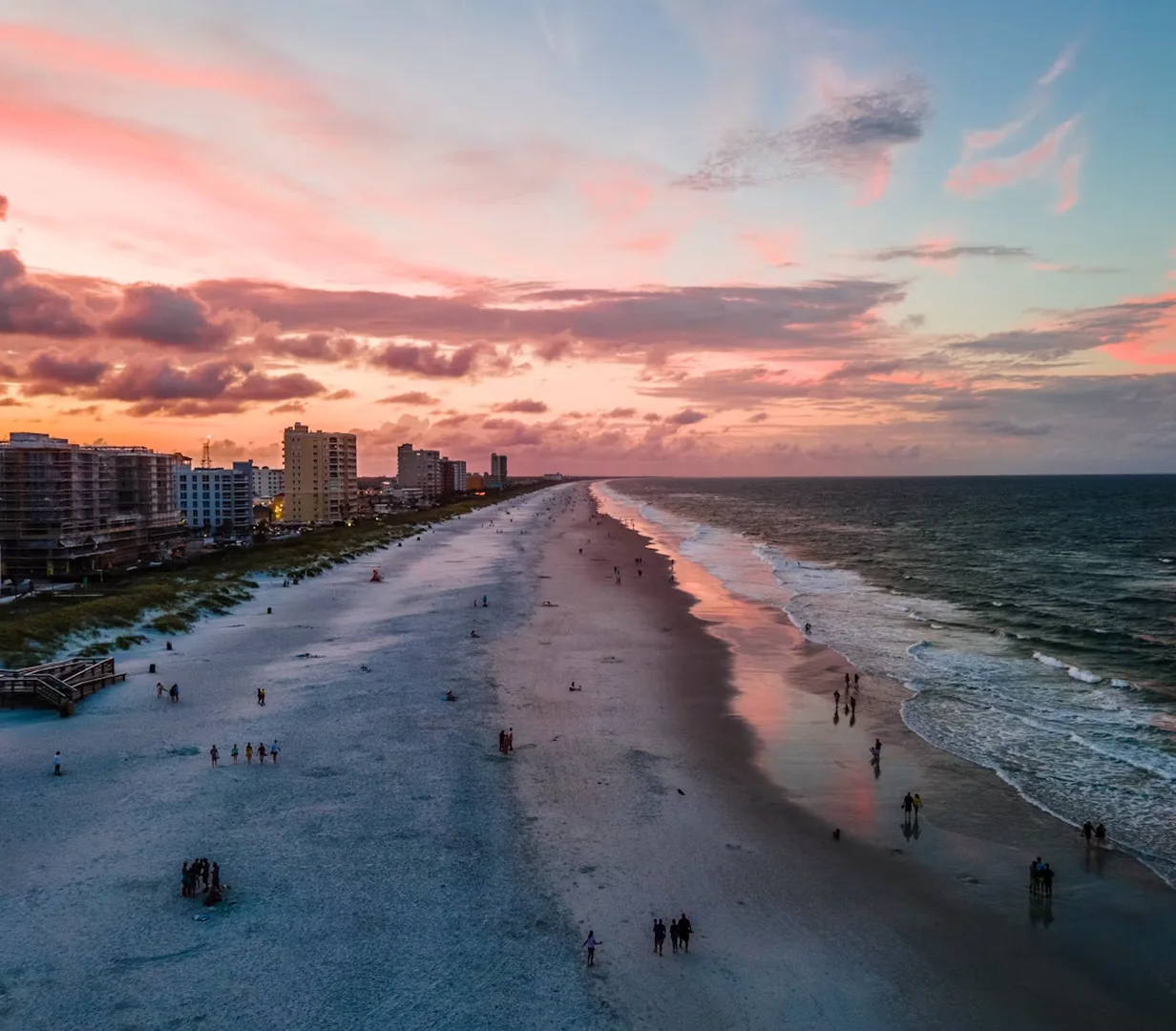 Aerial view of pink sunset skies over the ocean at the beaches near Jacksonville, Florida, a group day-trip destination for charter bus riders