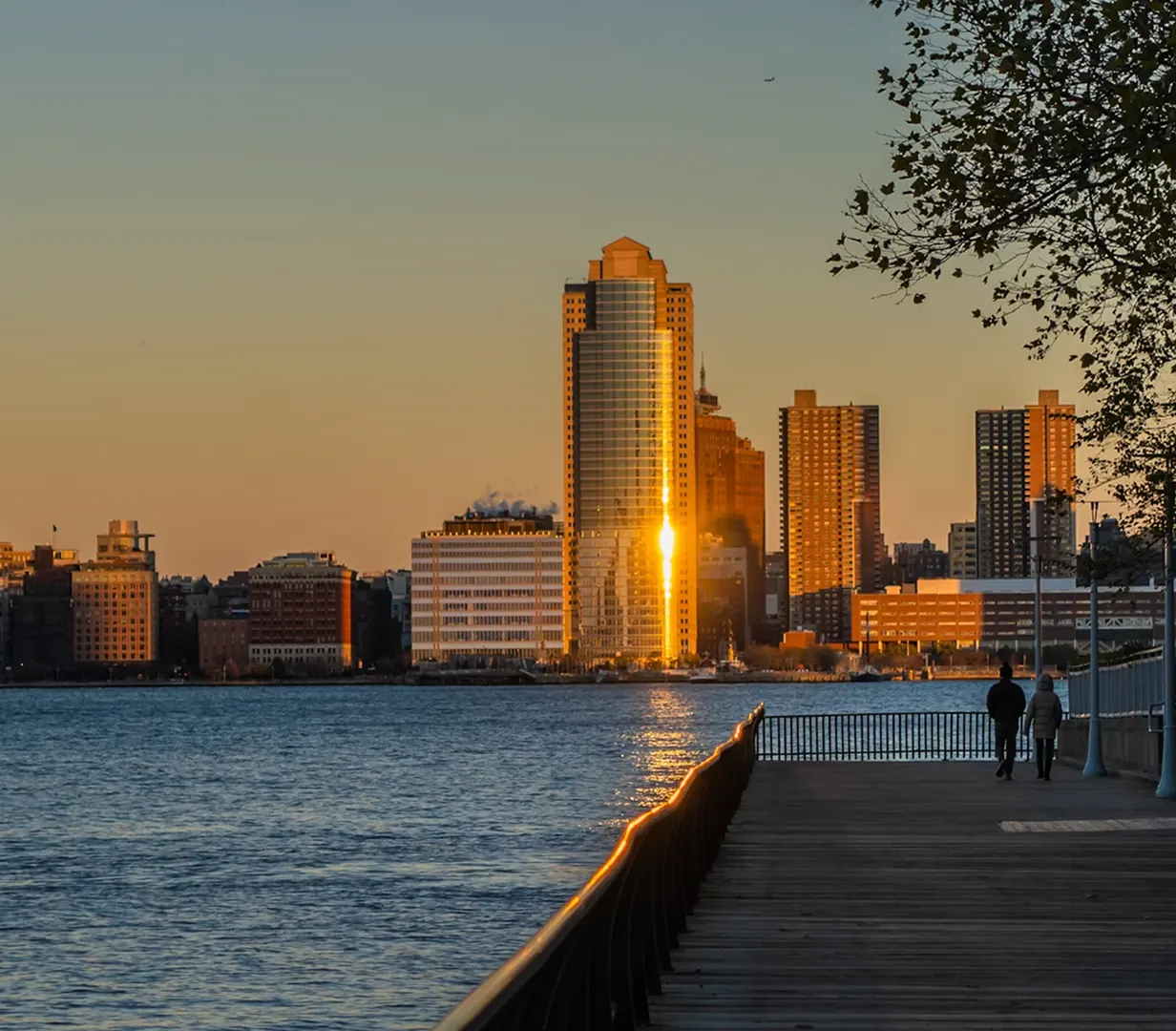 Waterfront boardwalk along the Hudson River at sunset in Jersey City, New Jersey, near the Exchange Place and Harborside charter bus pickup curbs