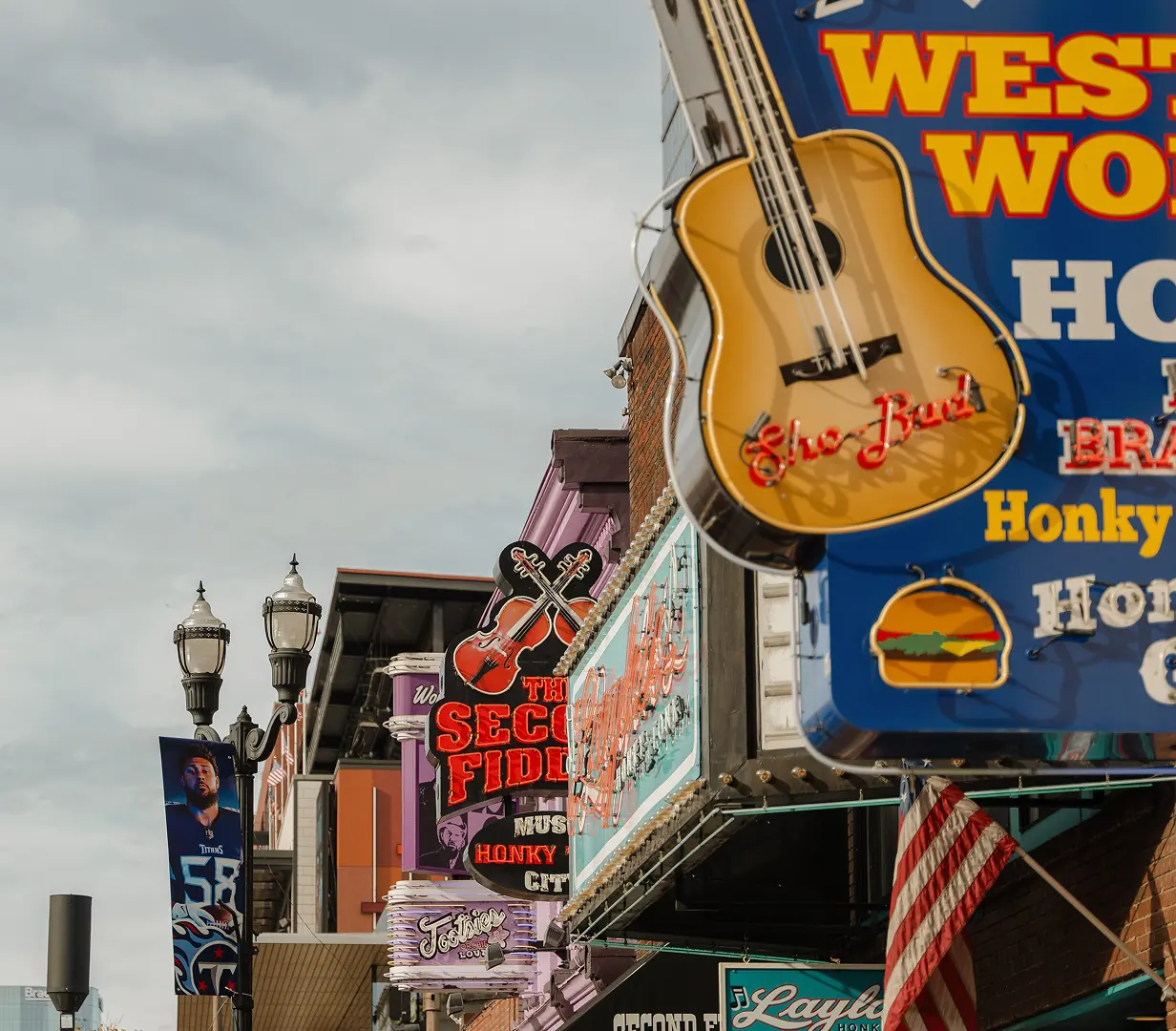 Neon guitar signs above the honky-tonks on Lower Broadway in Nashville, Tennessee, where charter bus groups are dropped a block off the strip