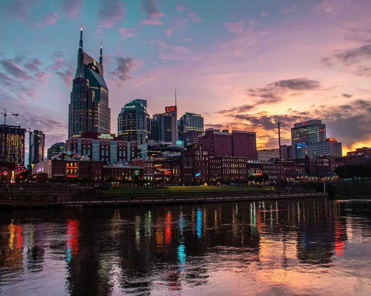 Downtown Nashville, Tennessee skyline and the AT&T Building above the Cumberland River at sunset, where charter bus groups stage for a night out