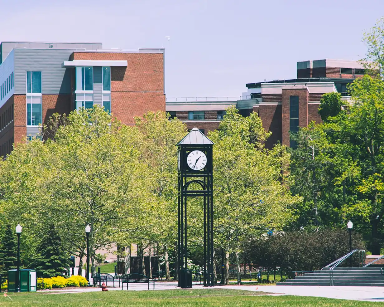 Campus clock tower framed by spring greenery in Rochester, New York, on the U of R / RIT campus visit route for charter bus groups