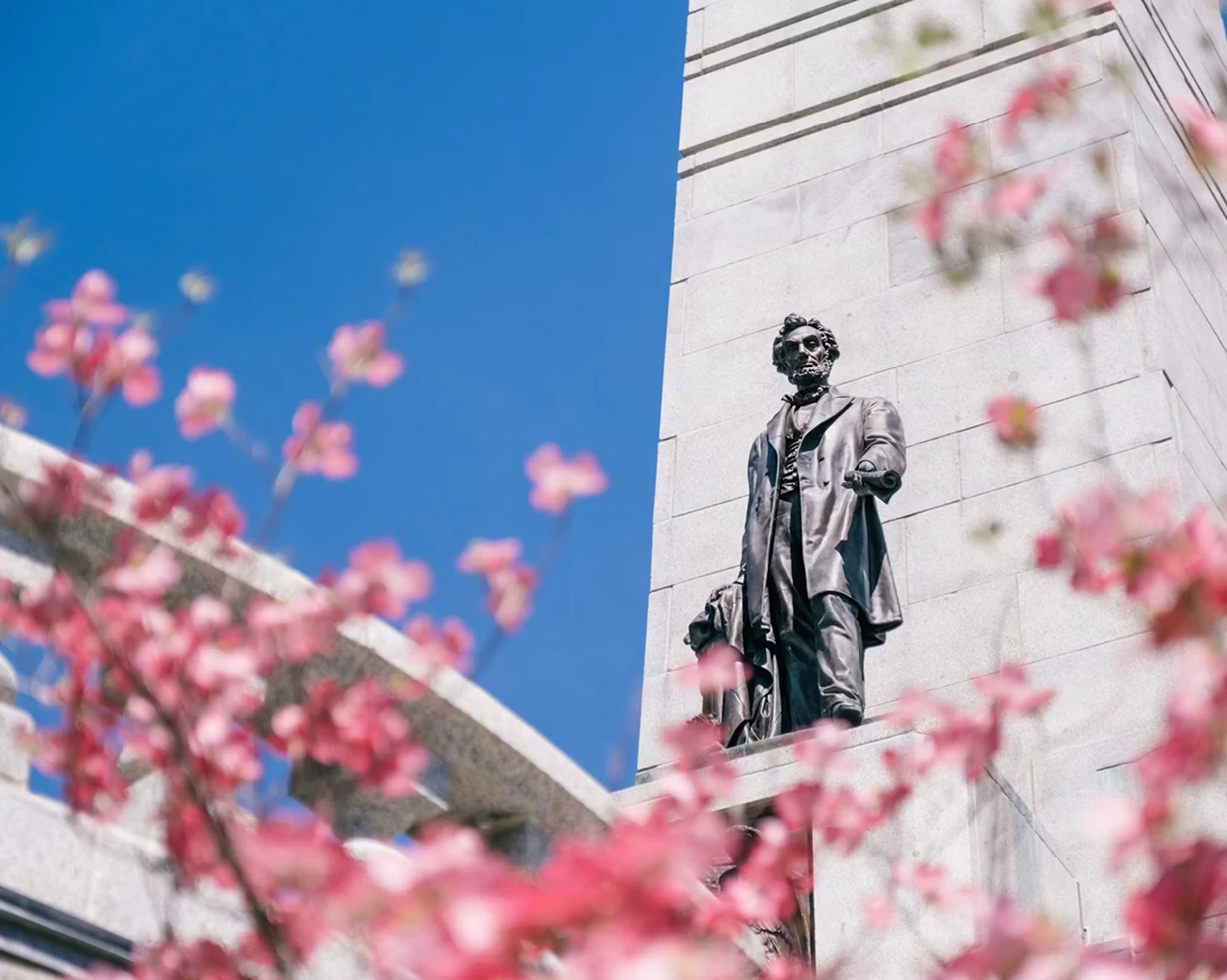 Abraham Lincoln statue framed by cherry blossoms in Springfield, Illinois, the anchor stop on charter bus Lincoln-site trips