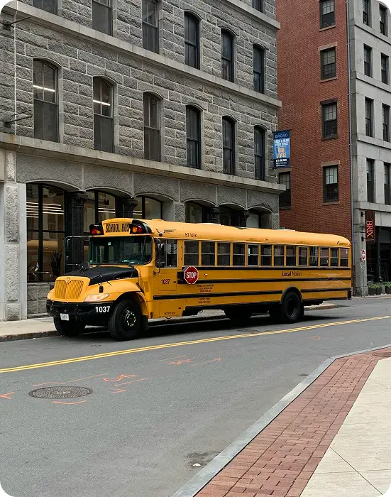 Tilted yellow school bus on city street.