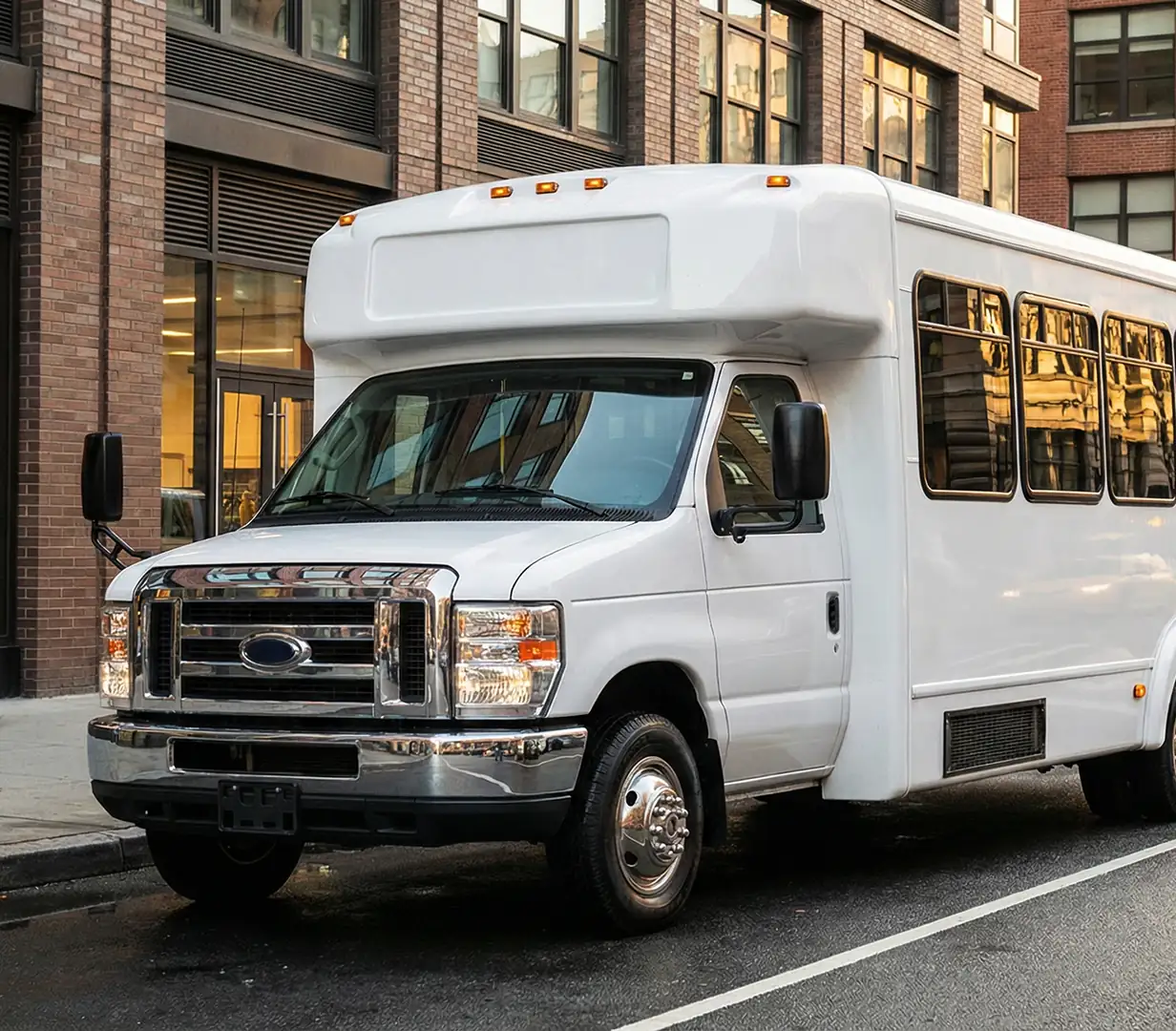 White shuttle bus parked by brick building.