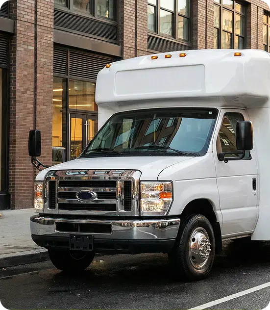 White shuttle bus parked by brick building.